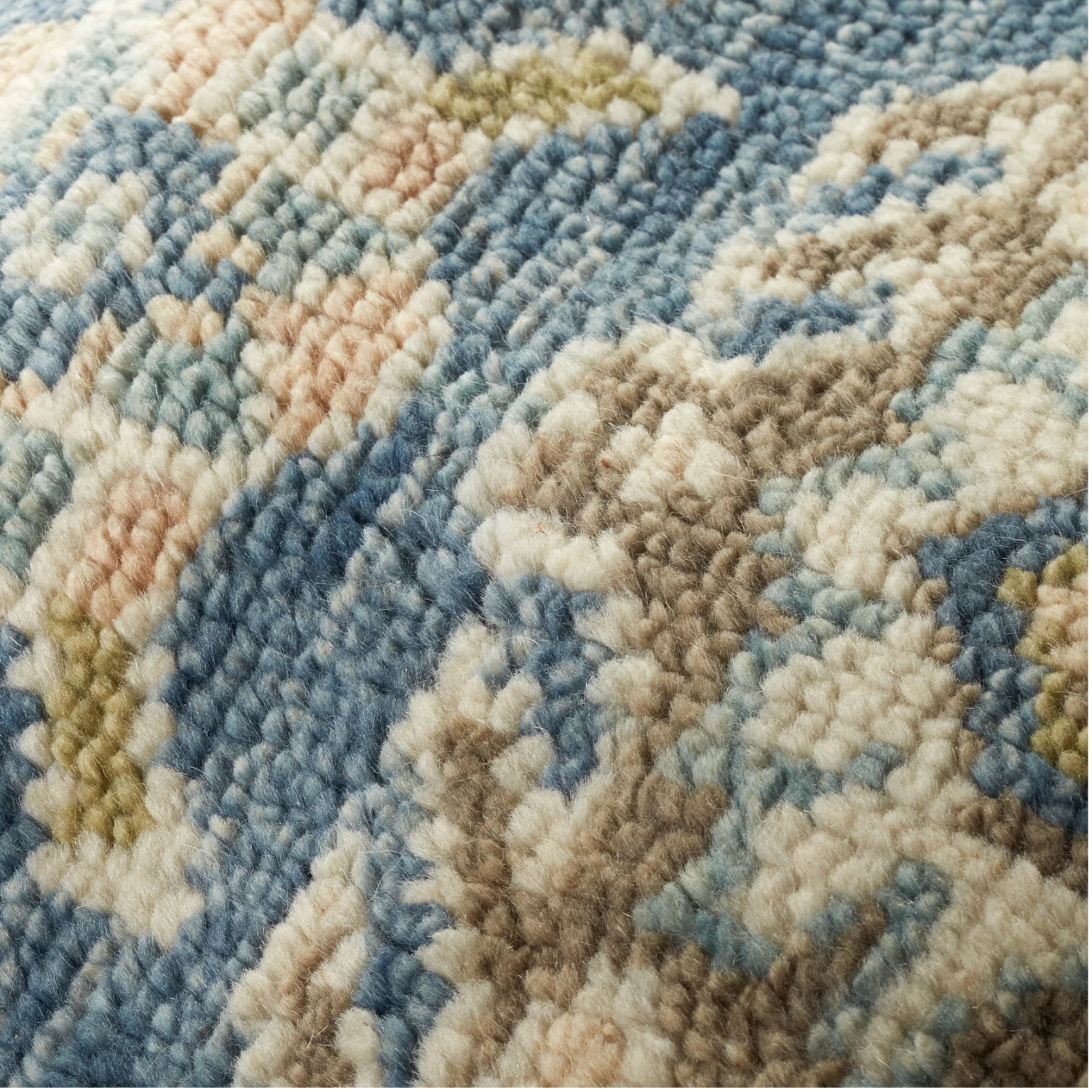 Close-up of a textured rug with geometric pattern in blue, beige, and green.