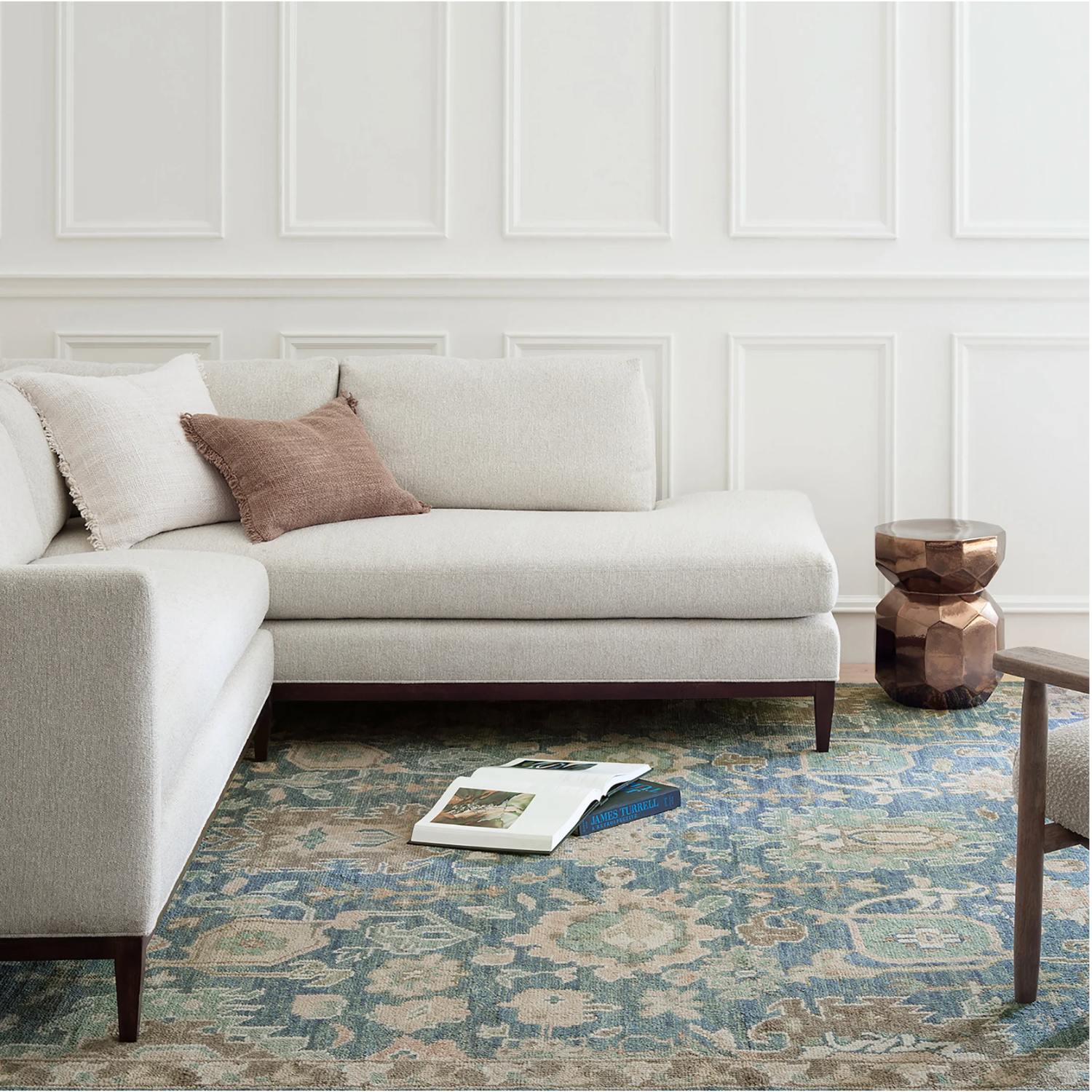 Living room with a beige sectional sofa, patterned rug, and wooden side table.