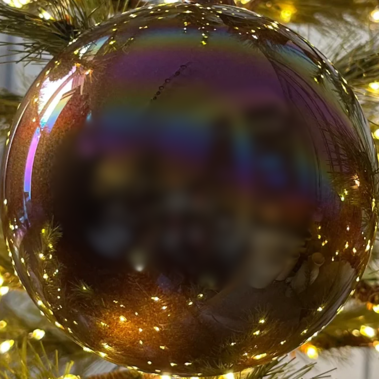 Iridescent Christmas ornament on a tree with lights