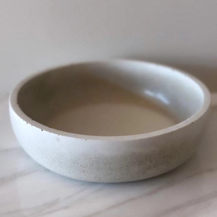 grey concrete bowl on a light wooden surface with a plain background
