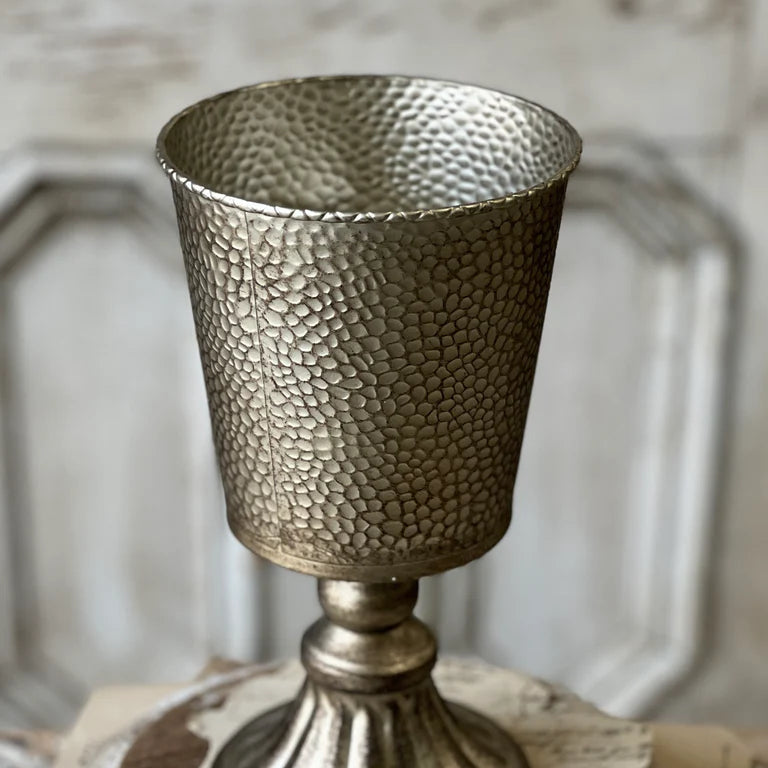 Decorative metallic goblet on a textured surface with a blurred background