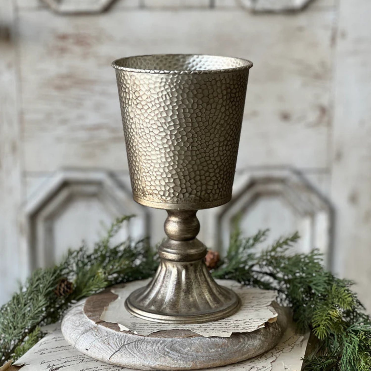 Decorative metallic goblet on a rustic wooden surface with greenery