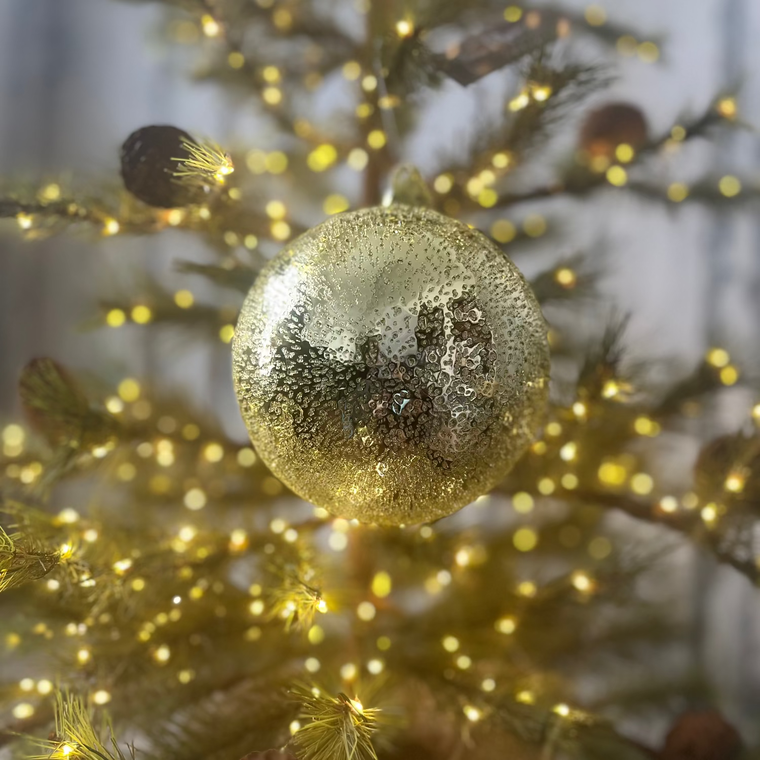 Decorative gold ornament on a Christmas tree with twinkling lights