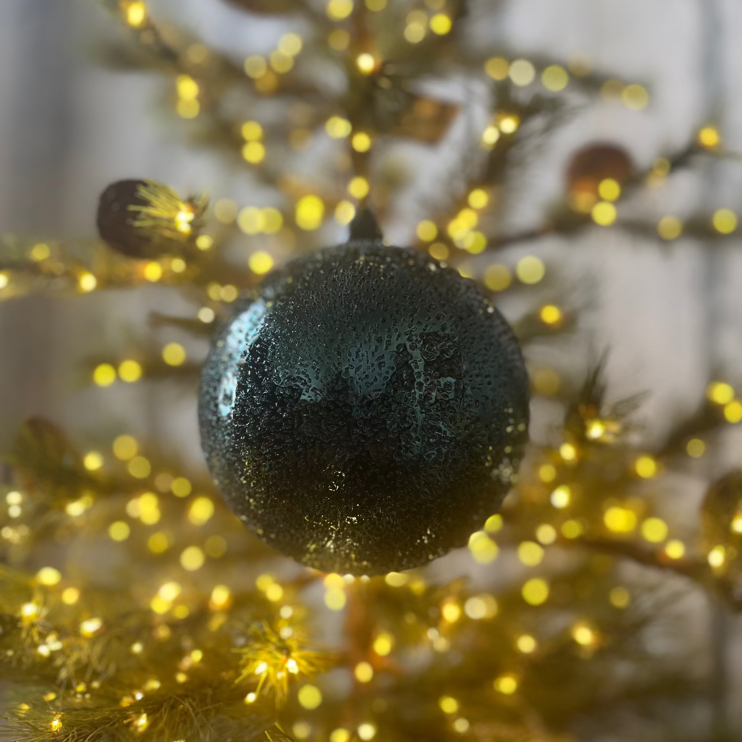 Black ornament on a decorated tree with gold lights