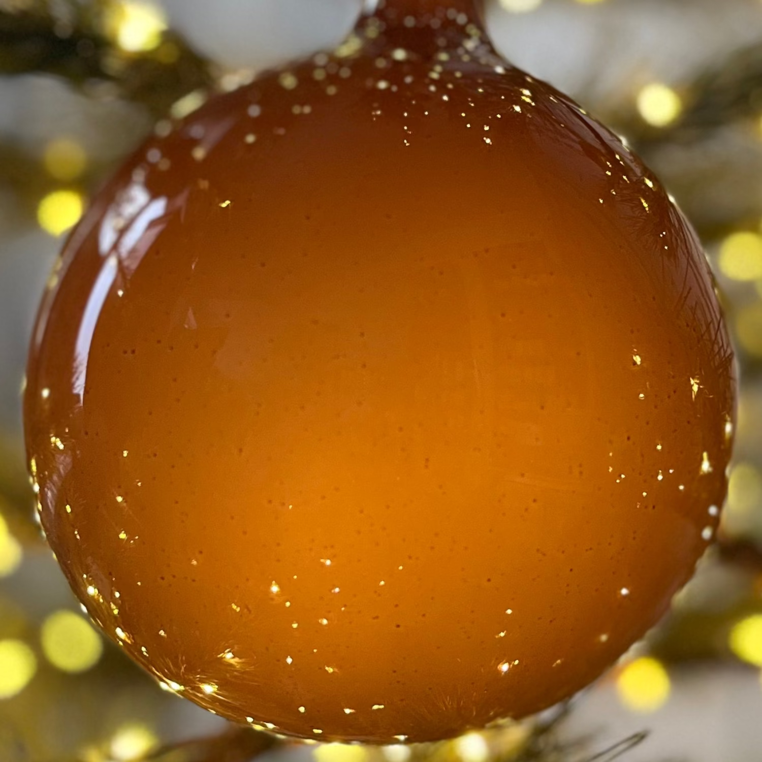 Decorative brown ornament on a lit Christmas tree with blurred lights in the background