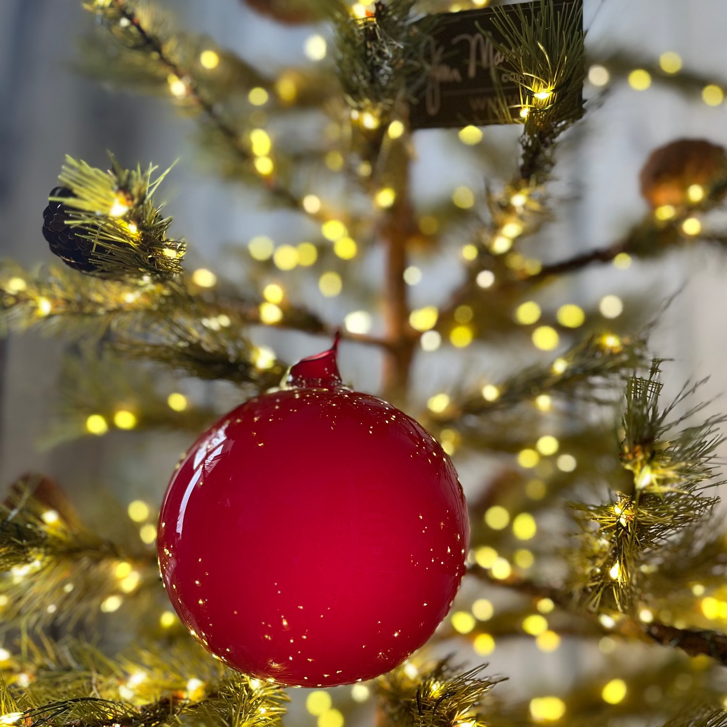 Red ornament on a decorated Christmas tree with lights