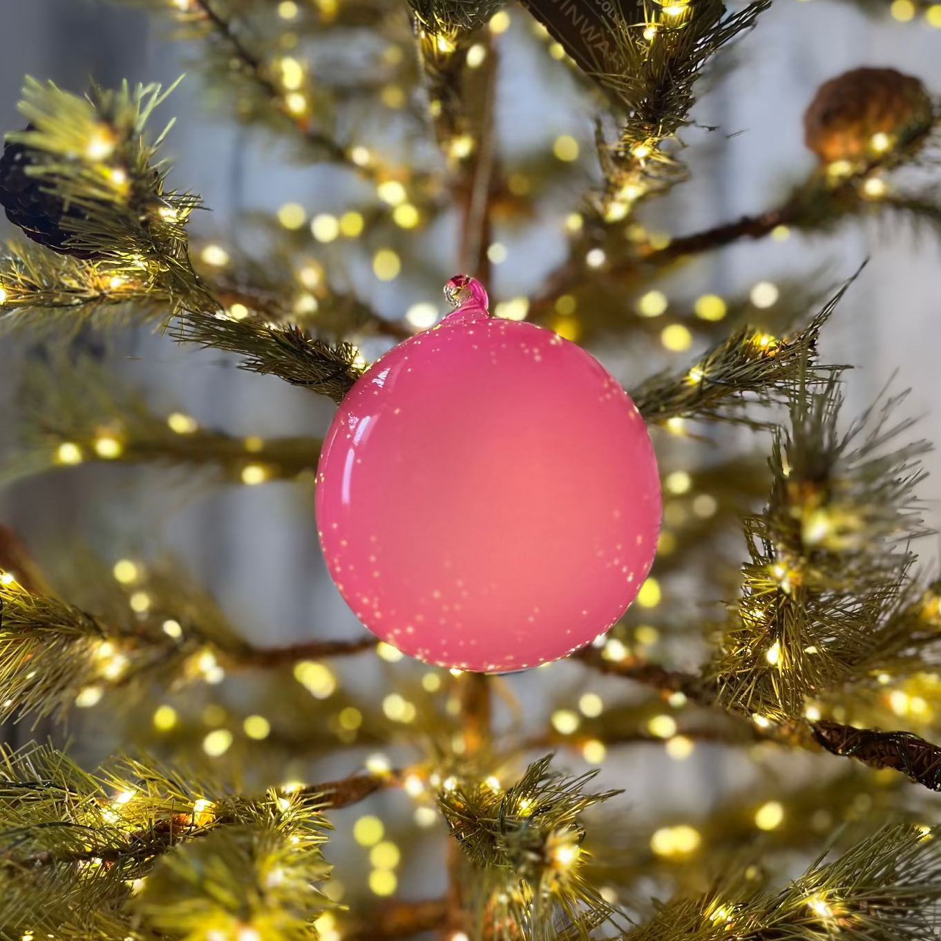 Pink ornament on a decorated Christmas tree with lights