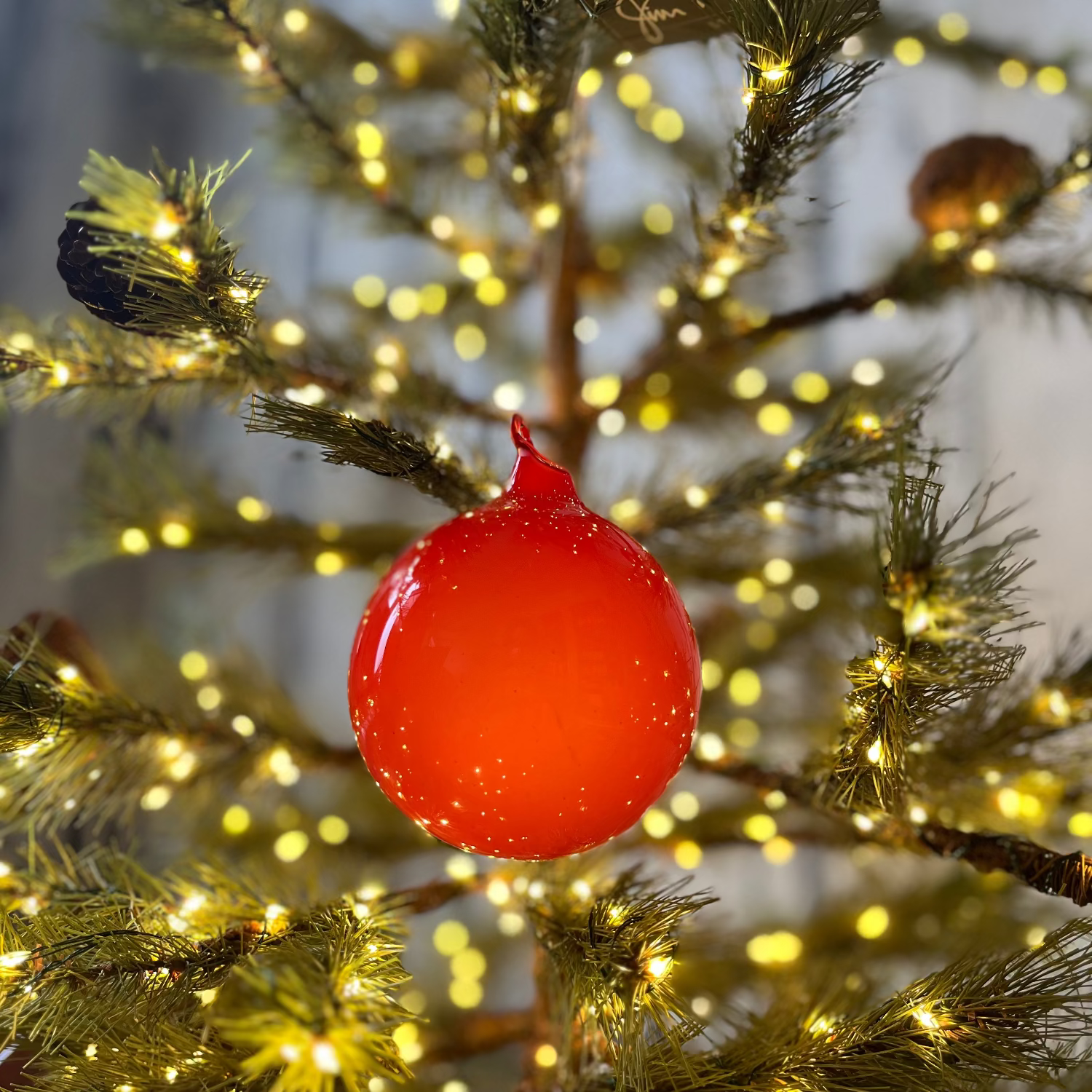 Red Christmas ornament on a decorated tree with lights