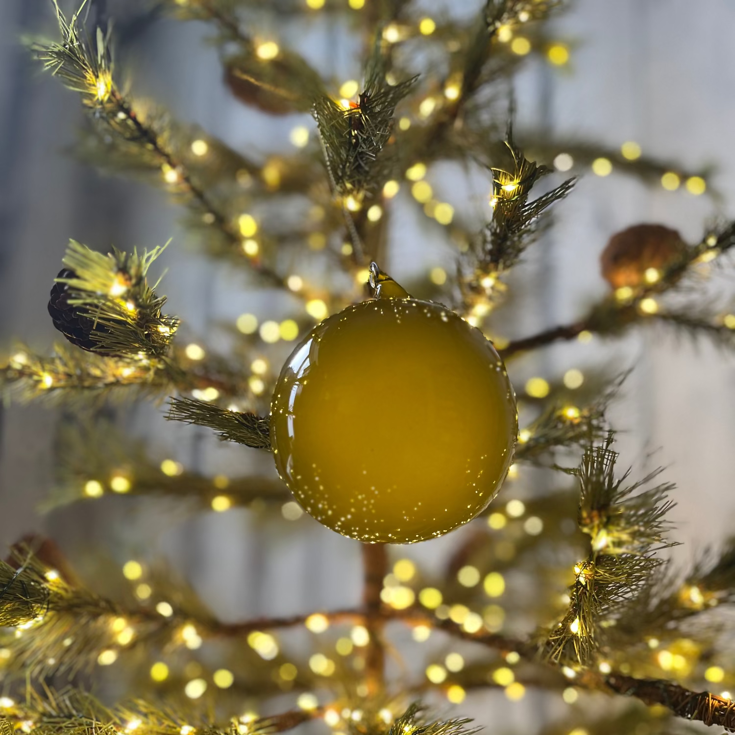 Yellow ornament on a decorated tree with lights