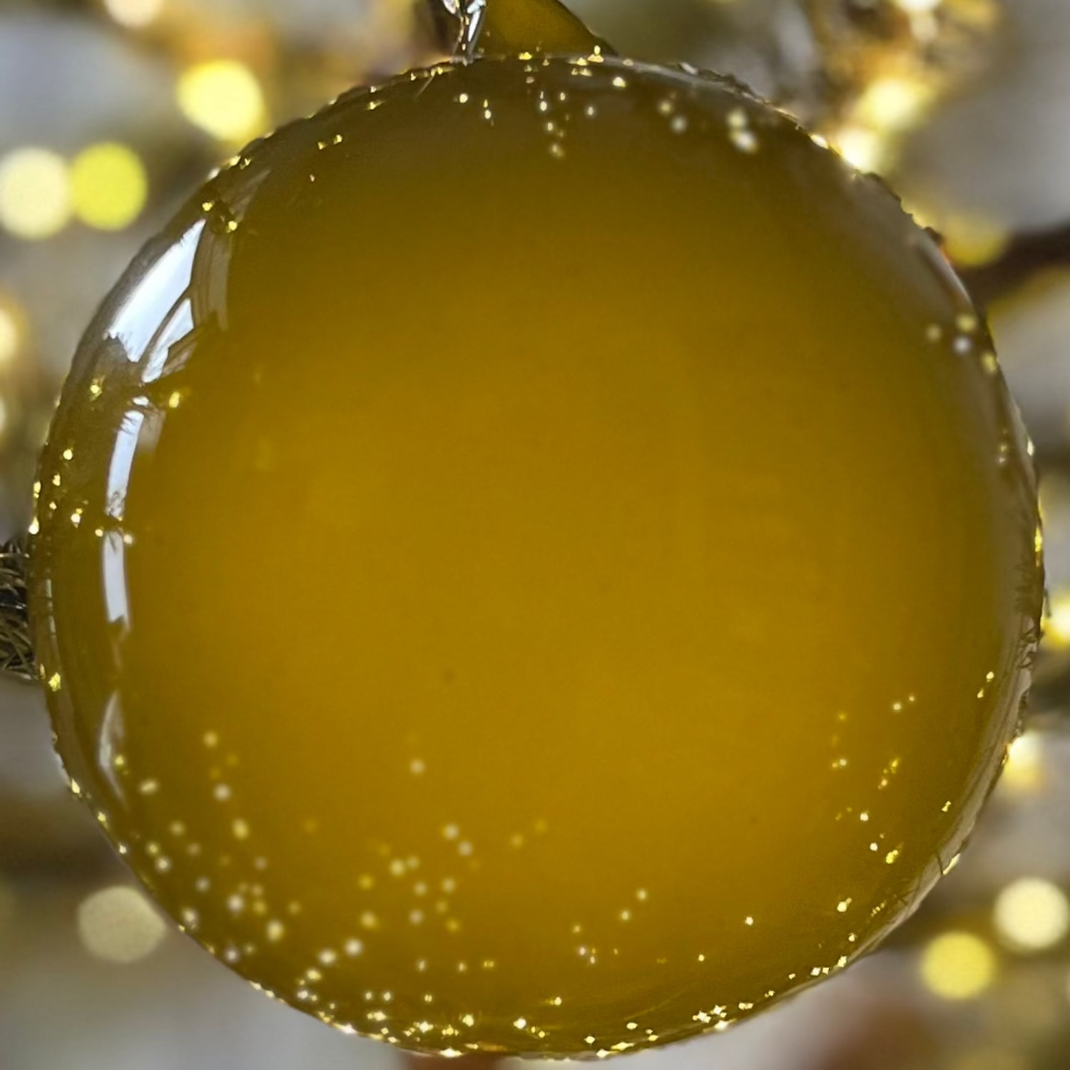 Decorative yellow ornament on a lit Christmas tree with a blurred background