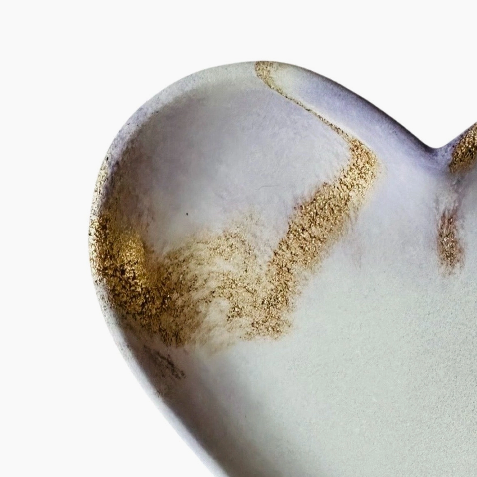 Close-up of a ceramic heart with gold accents on a white background