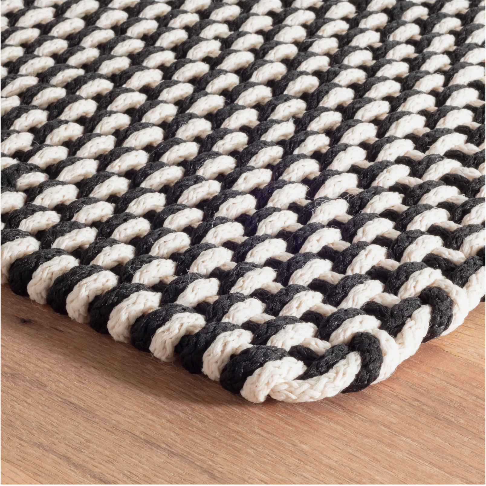 Black and white braided rug on a wooden floor