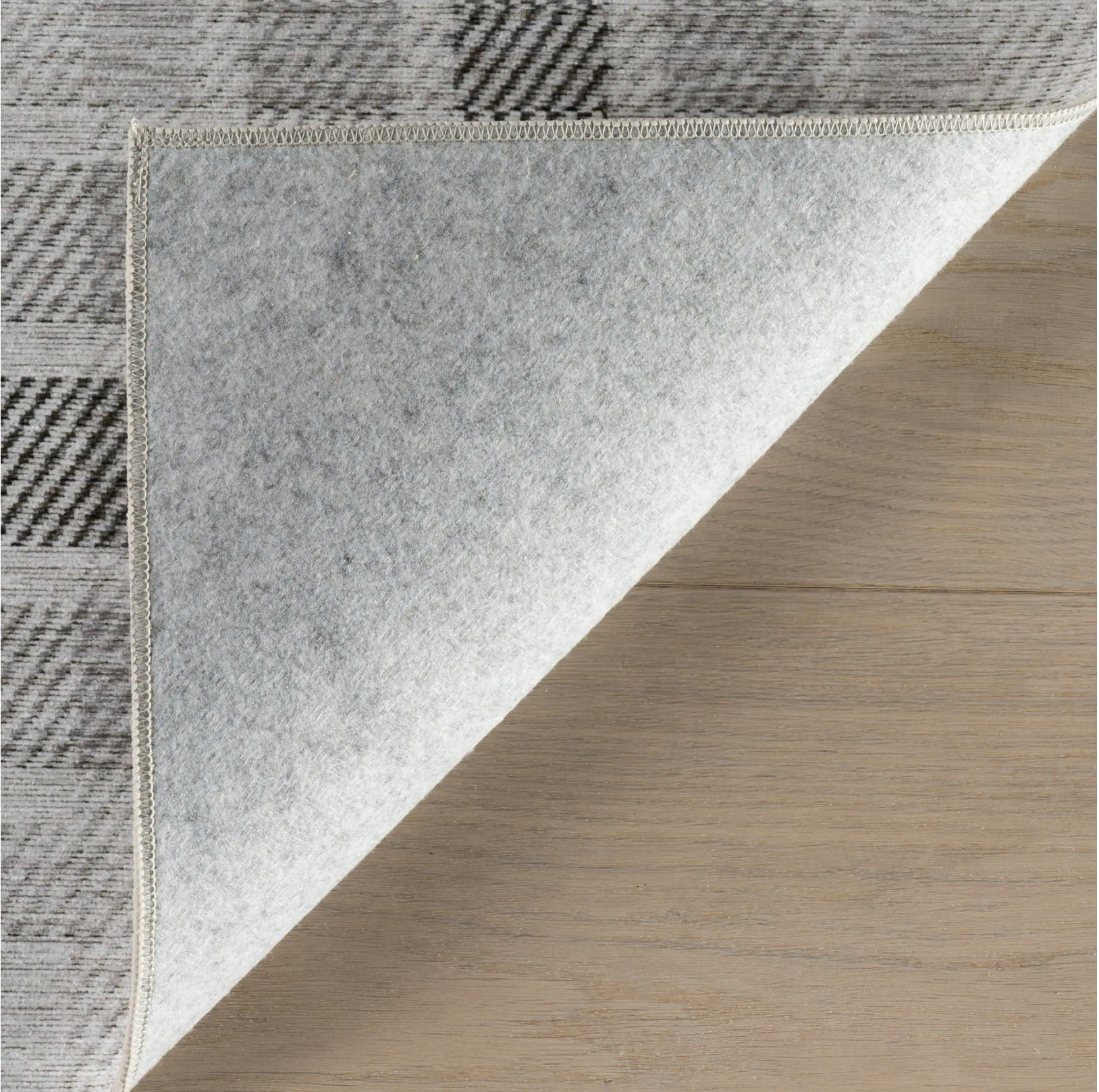 Close-up of a textured rug with geometric patterns on a wooden floor.