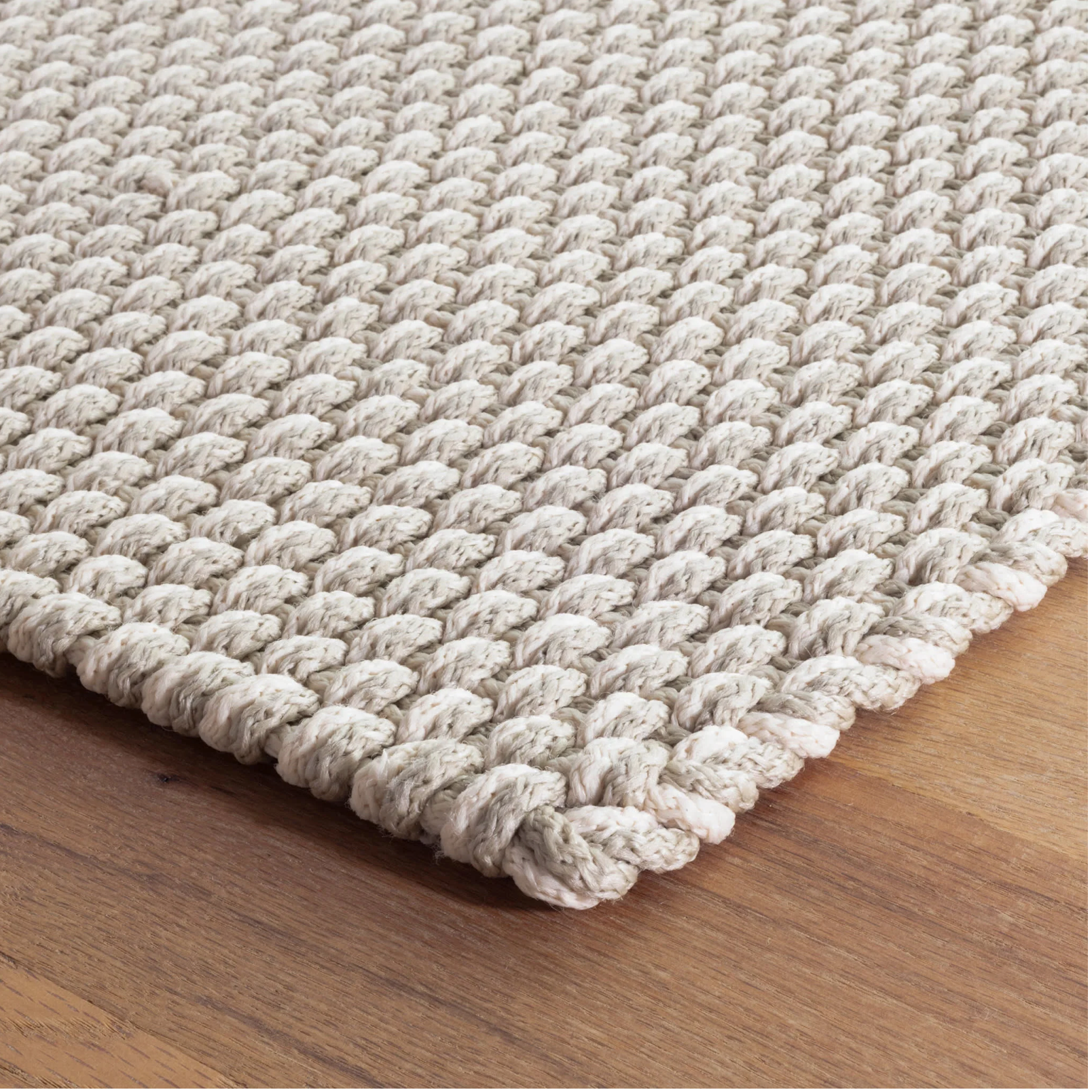 Textured beige rug on a wooden floor