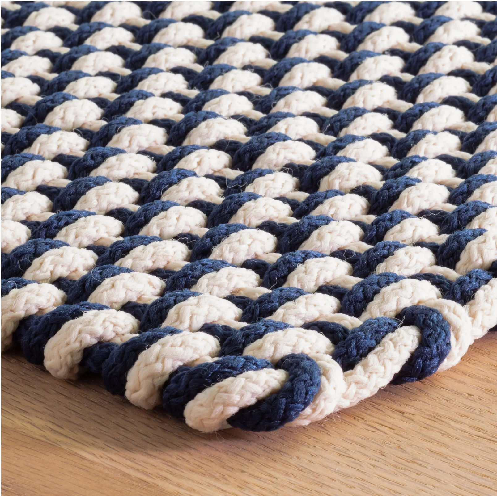 Navy and white braided rug on a wooden floor