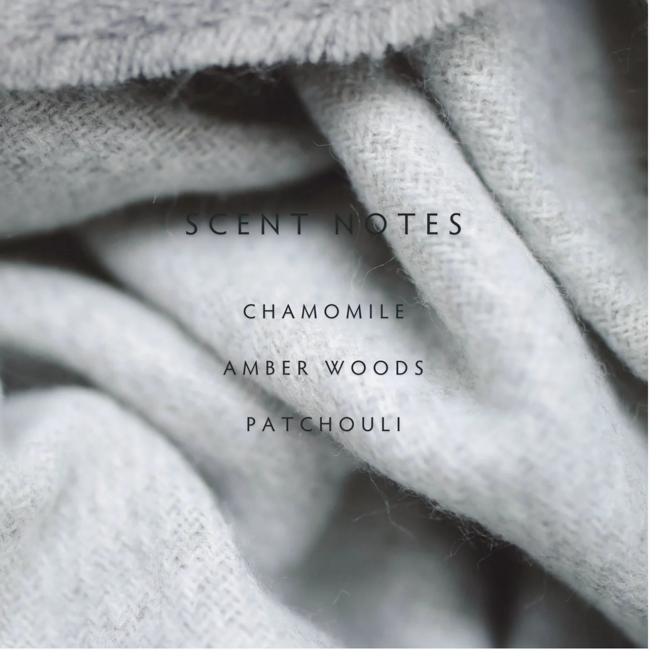 Text displaying 'SCENT NOTES' with 'Chamomile', 'Amber Woods', and 'Patchouli' on a textured fabric background.