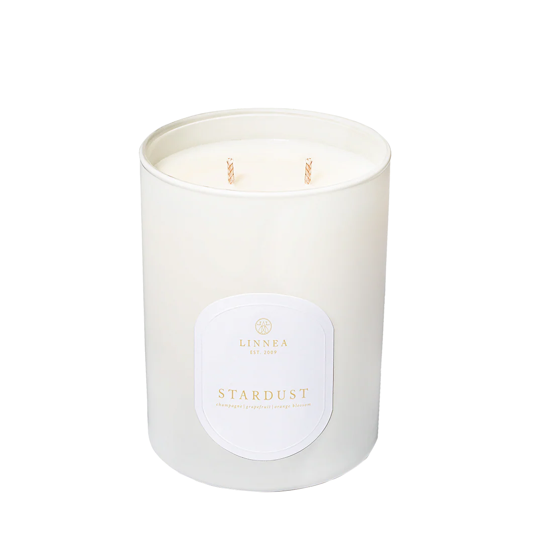 White candle in a glass jar with a label on a white background