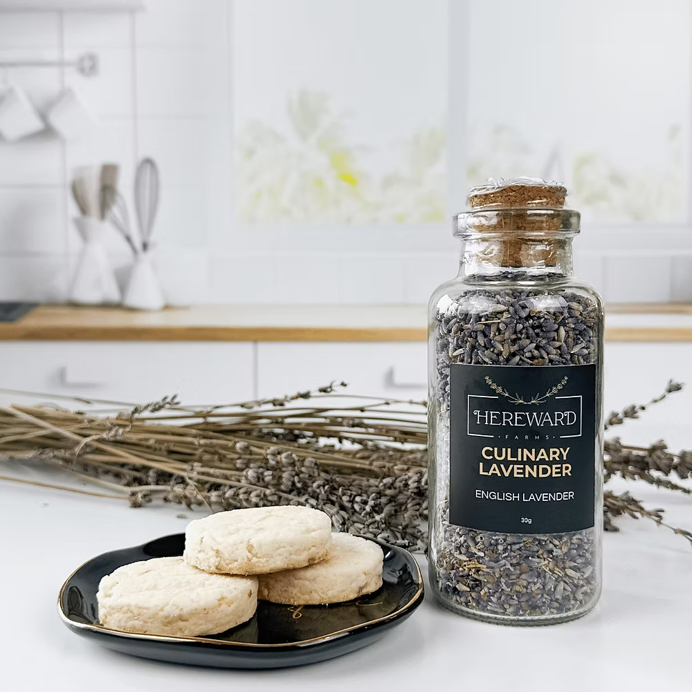 Bottle of culinary lavender from Hereward Farms with cookies on a plate in a kitchen setting.