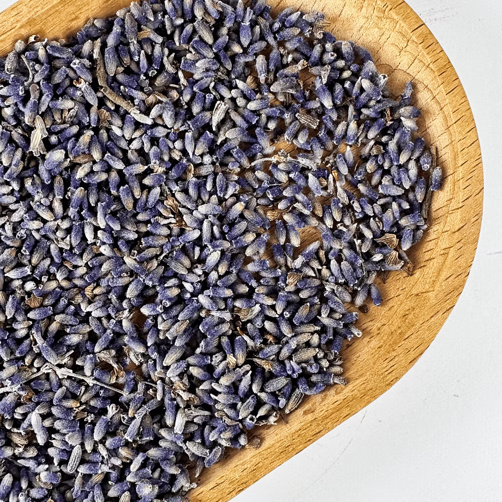 Dried lavender flowers in a wooden bowl on a white background