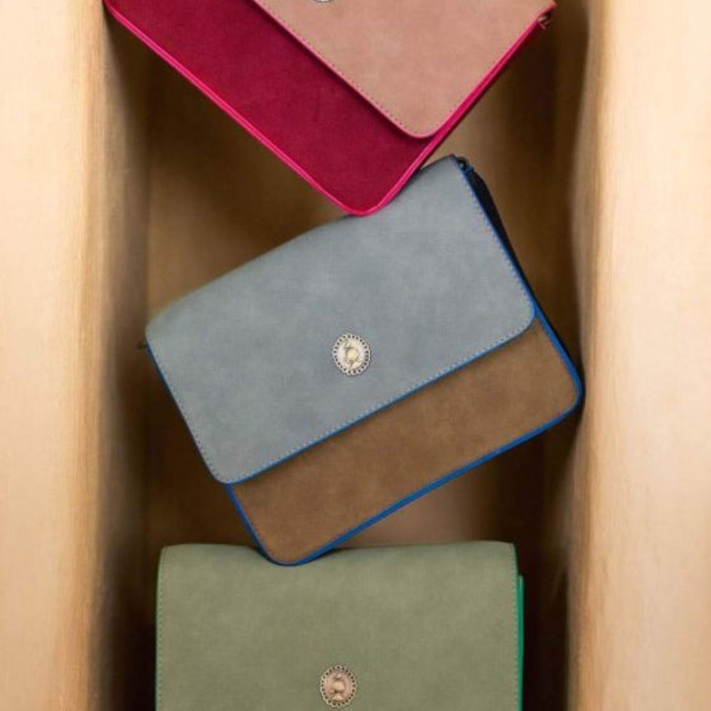 Three colorful bags stacked on a textured beige surface