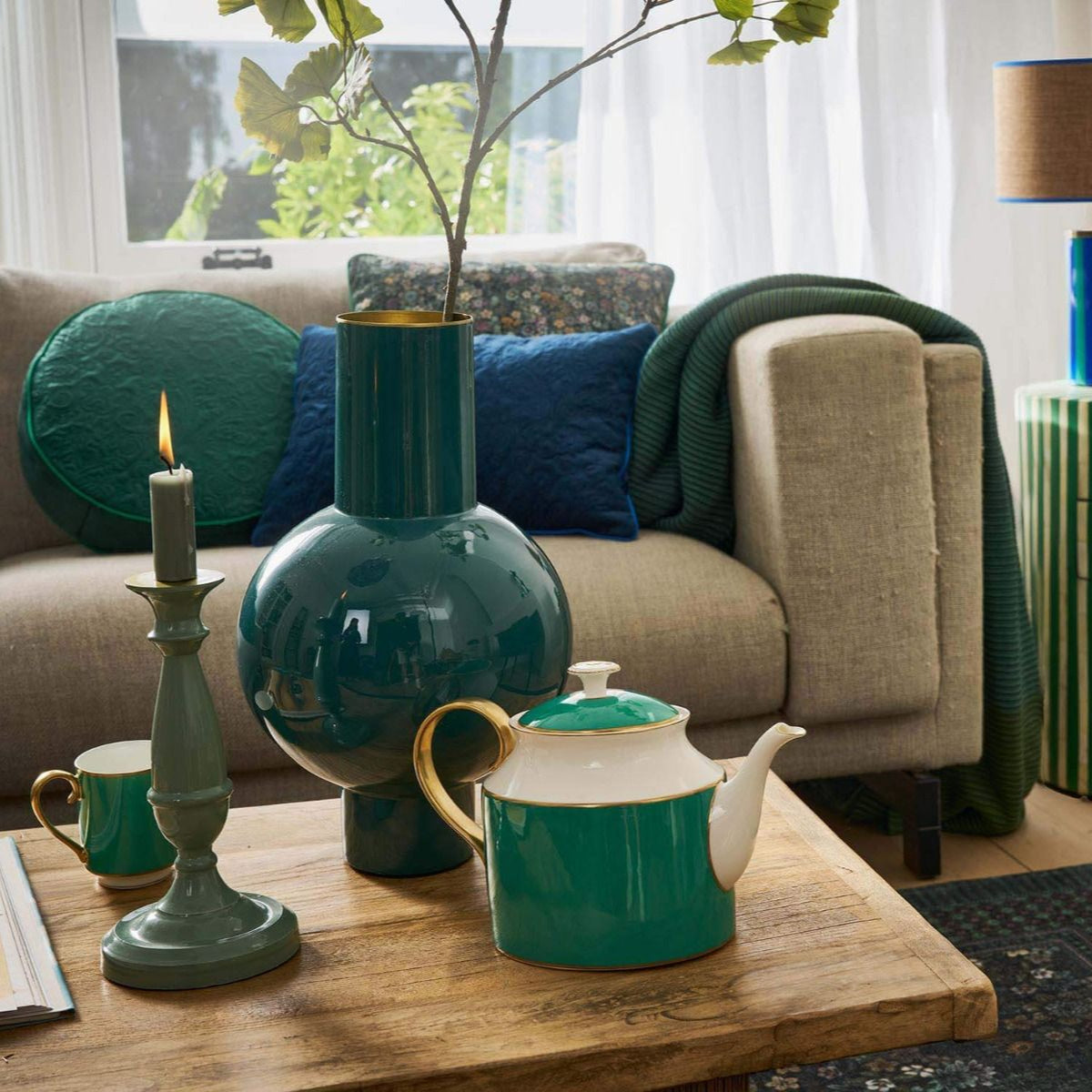 Living room with teal decor, including a teapot and candlesticks on a wooden coffee table.
