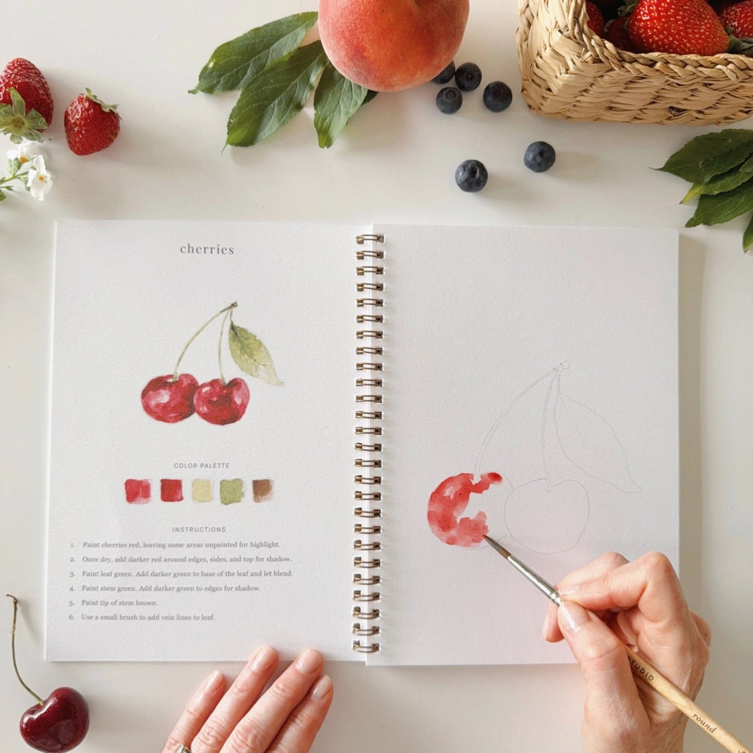 Open watercoclour workbook with fruit designs