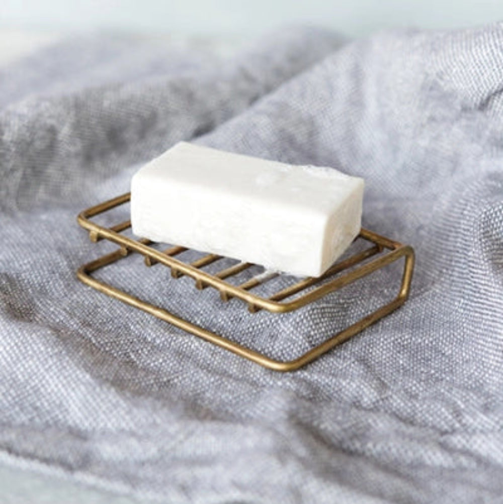 Bar of soap on a brass soap dish with a soft fabric background