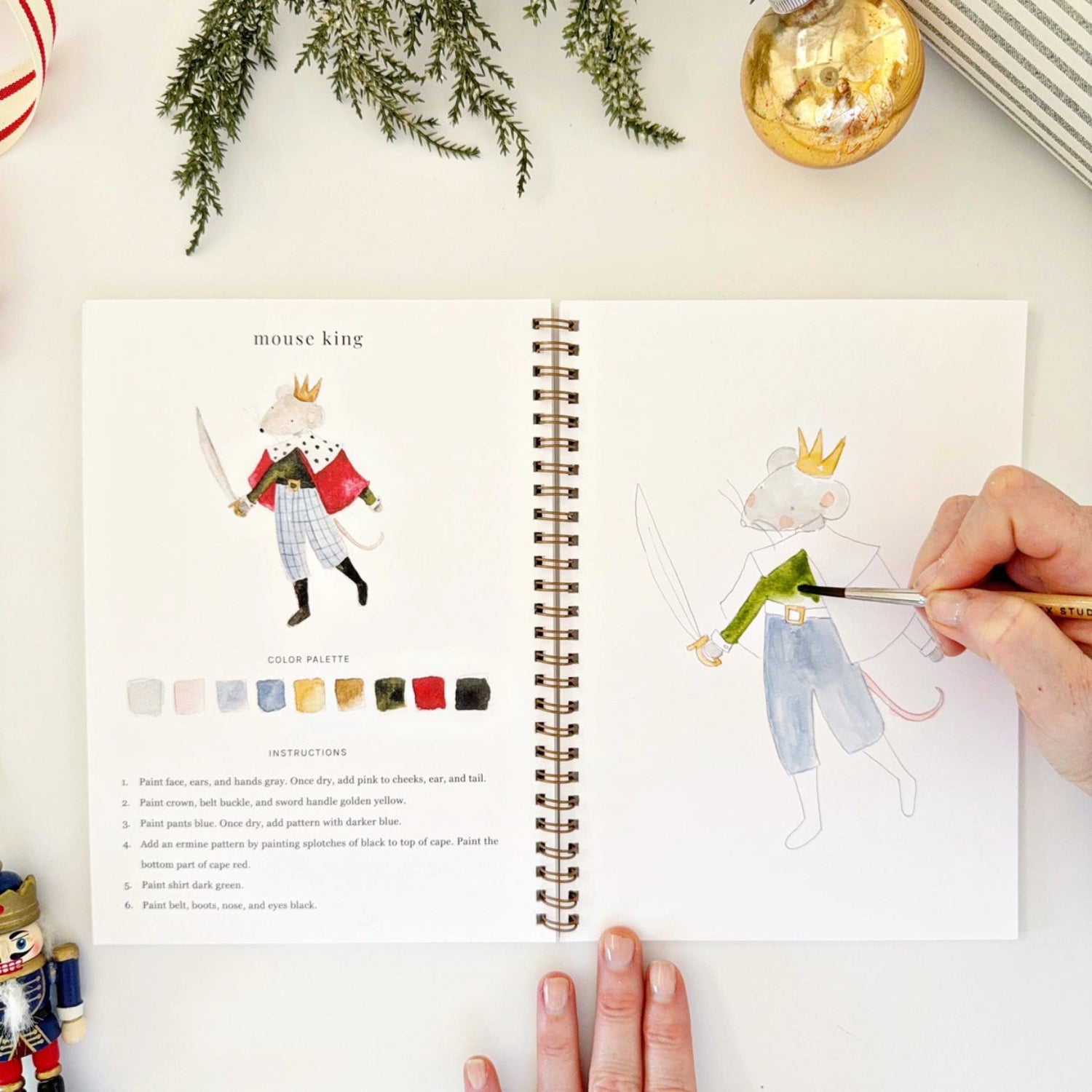 Person drawing a character in a notebook with a color palette and instructions.