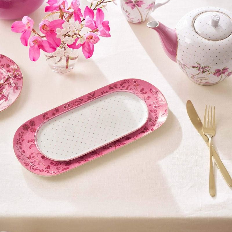 Pink and white ceramic items including a teapot, tray, and cups on a light background.