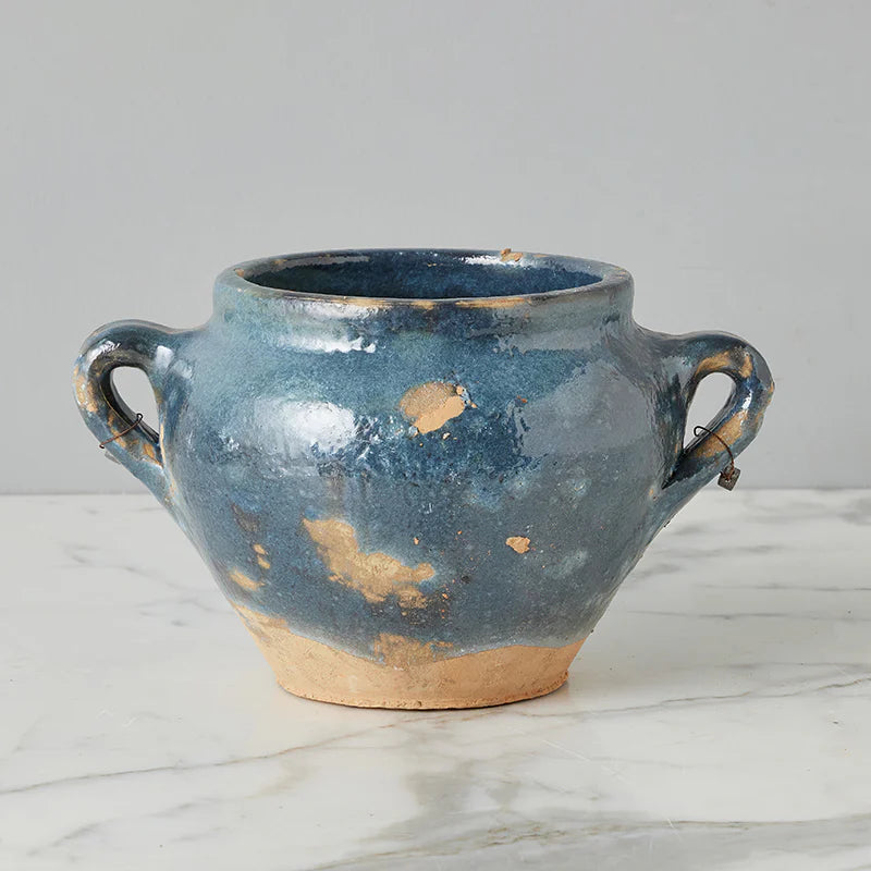 Blue ceramic vase with two handles on a marble surface