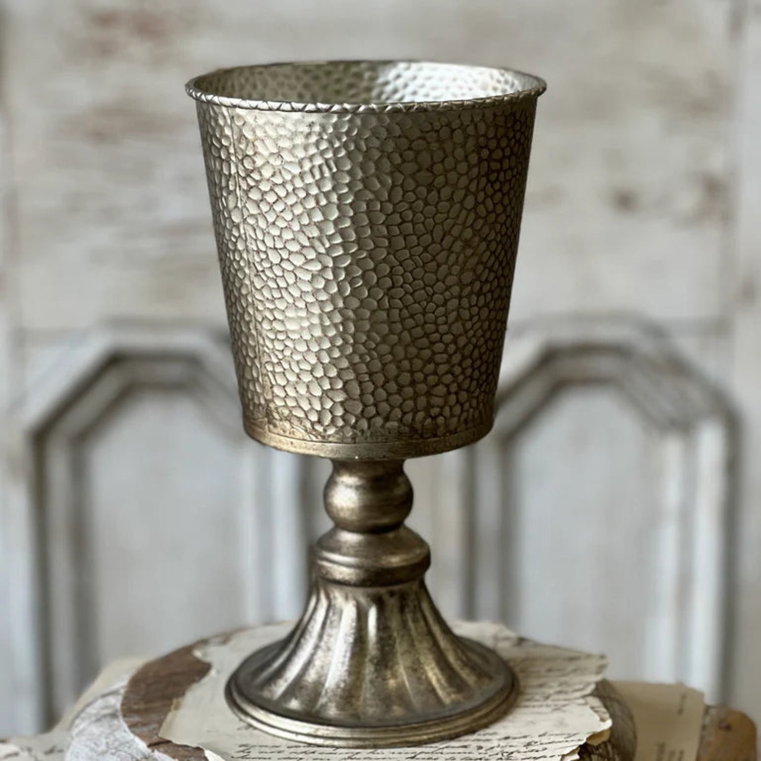 Decorative metallic goblet on a wooden stand with a textured background