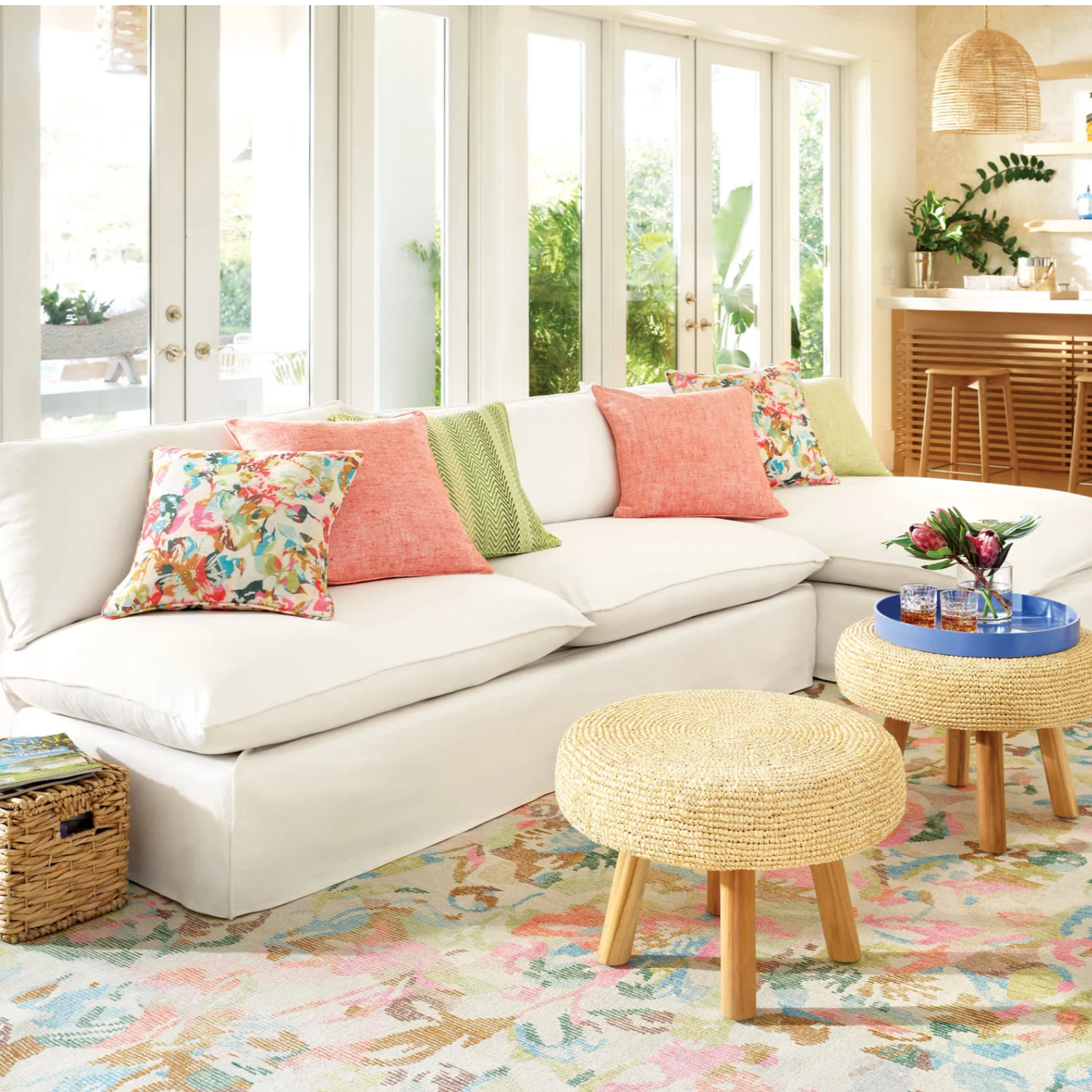 Living room with a white sectional sofa, colorful pillows, and a floral rug.