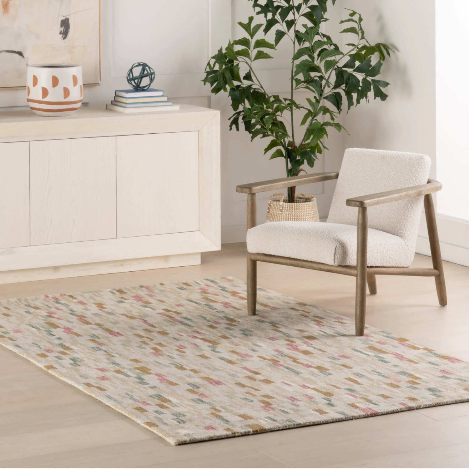 Living room with a chair, rug, and plant on a light wood floor.
