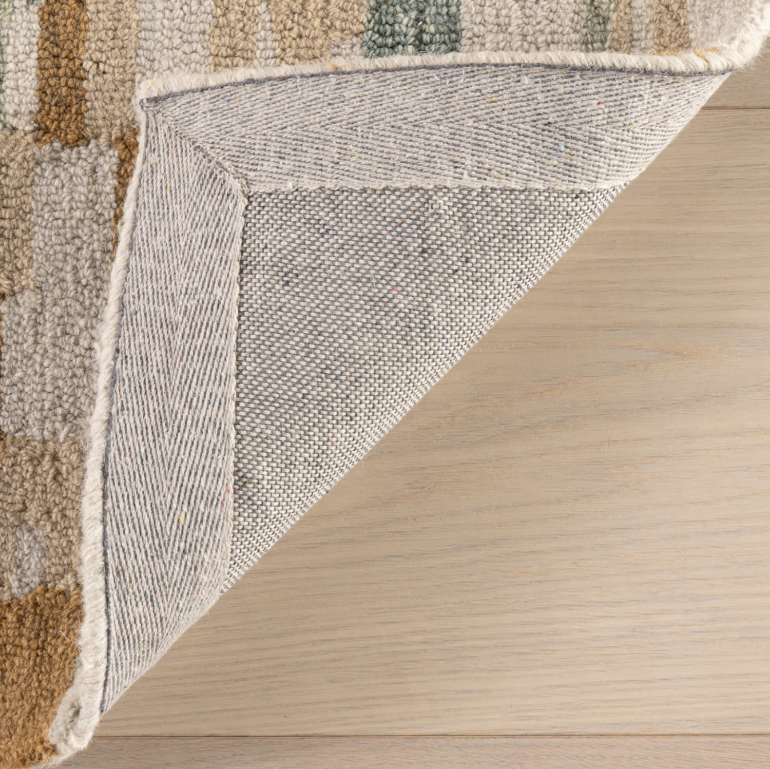 Close-up of a textured rug corner on a wooden floor