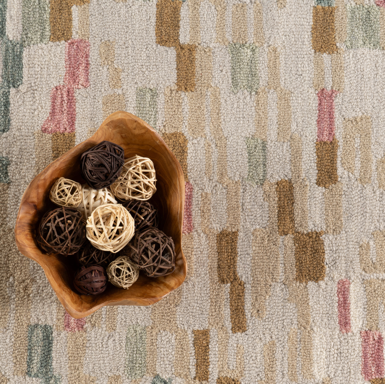 Wooden bowl with decorative balls on a patterned carpet