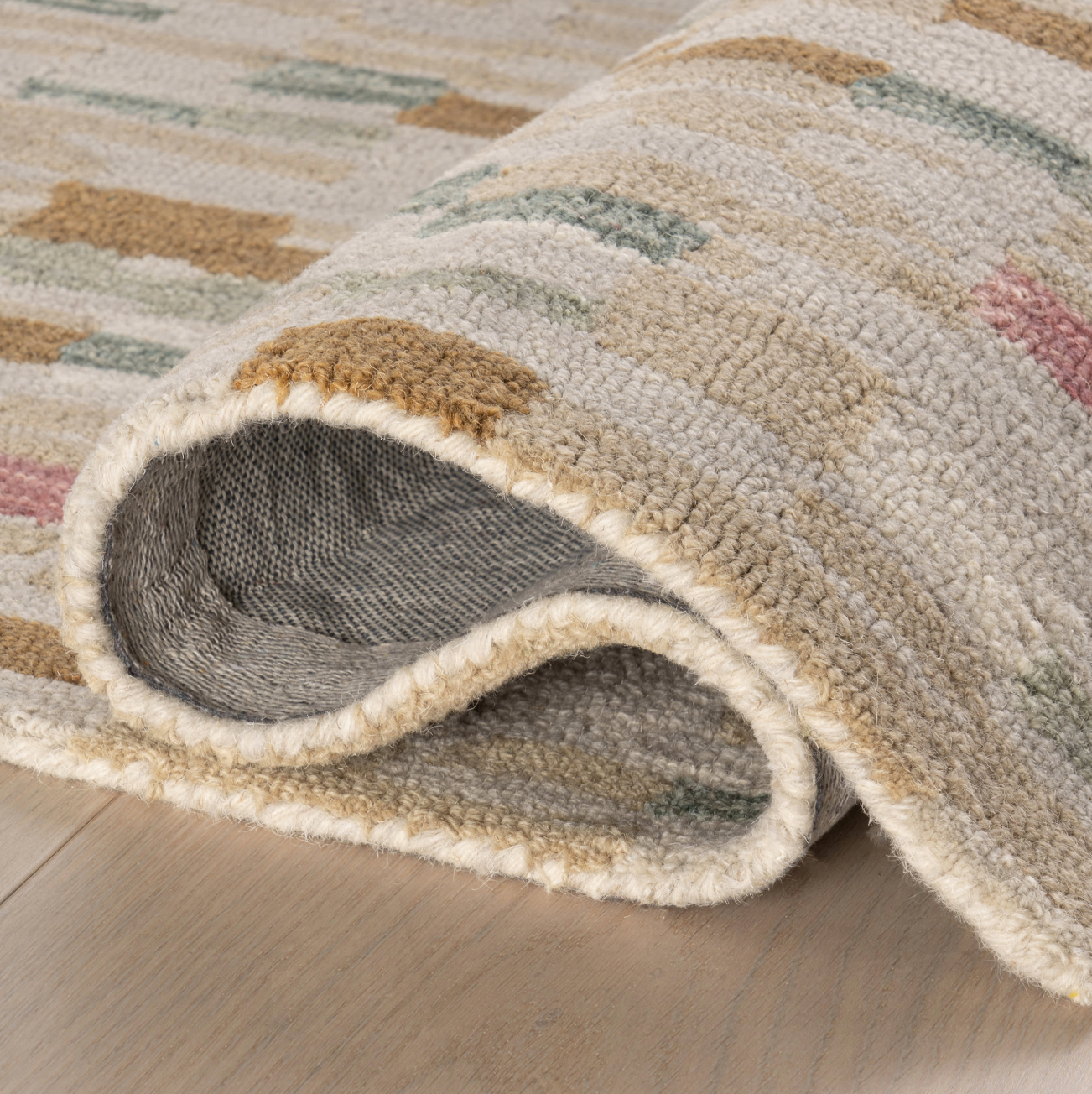 Close-up of a textured rug with geometric pattern on a wooden floor