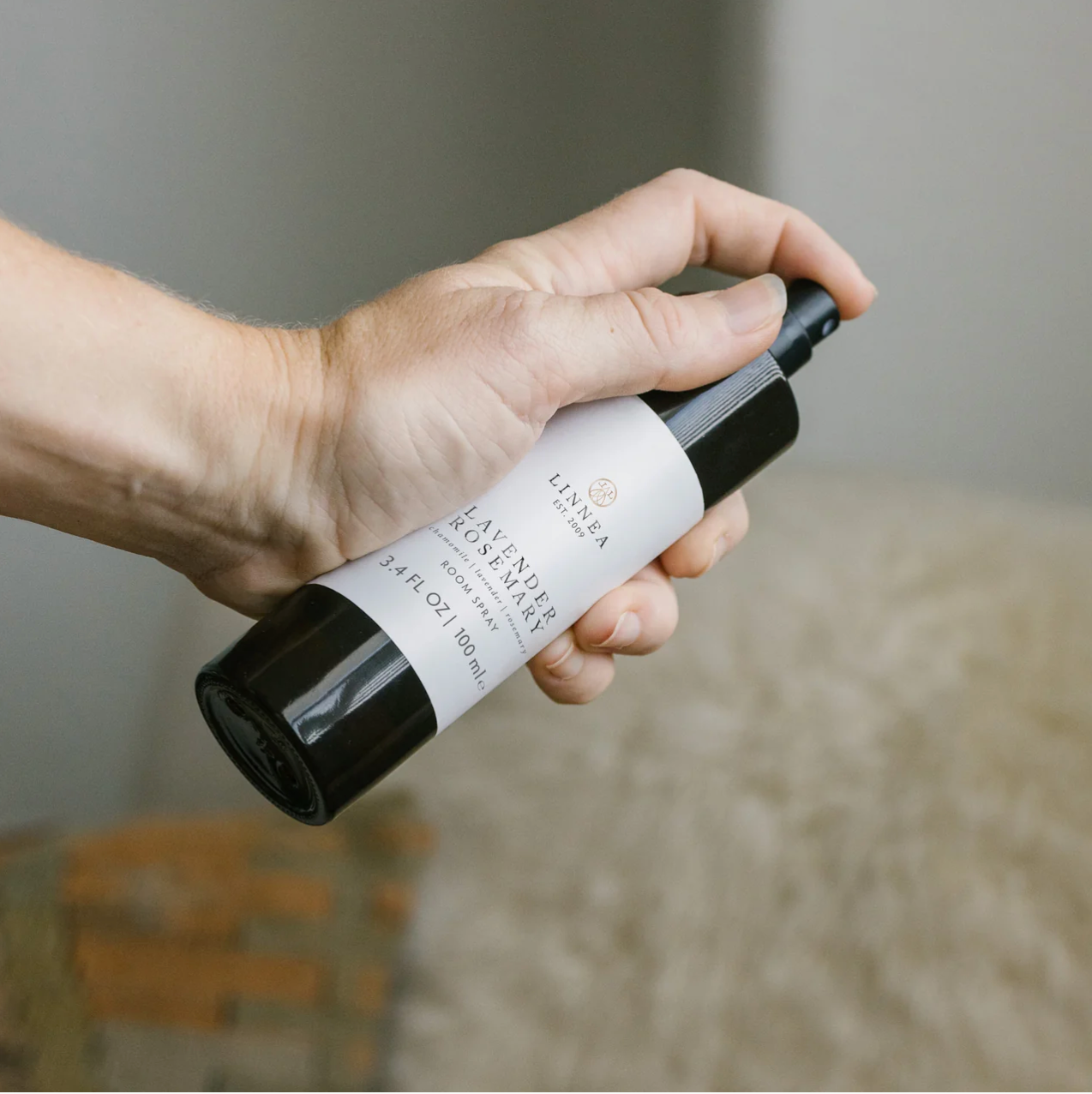 Hand holding a black and white bottle with a label, against a blurred background
