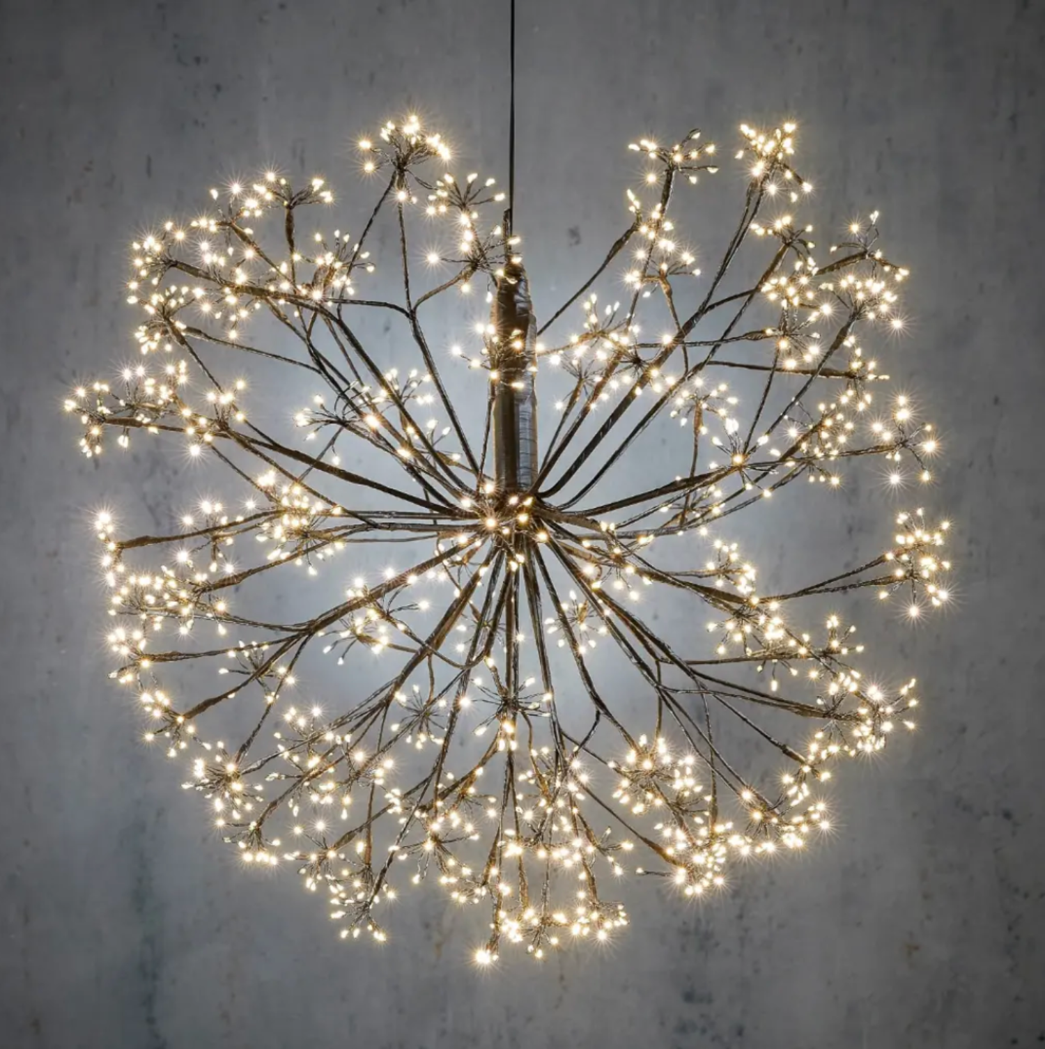 Decorative light fixture with branches and LED lights on a textured wall background