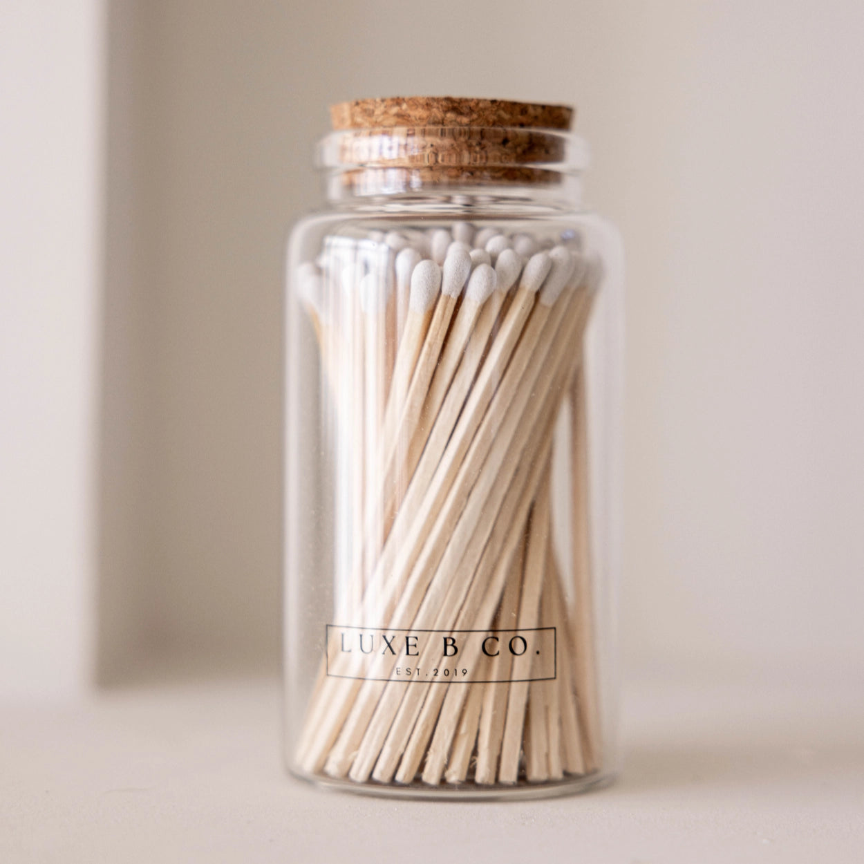 Jar of matches with cork lid and 'LUXE B. CO.' branding on a neutral background