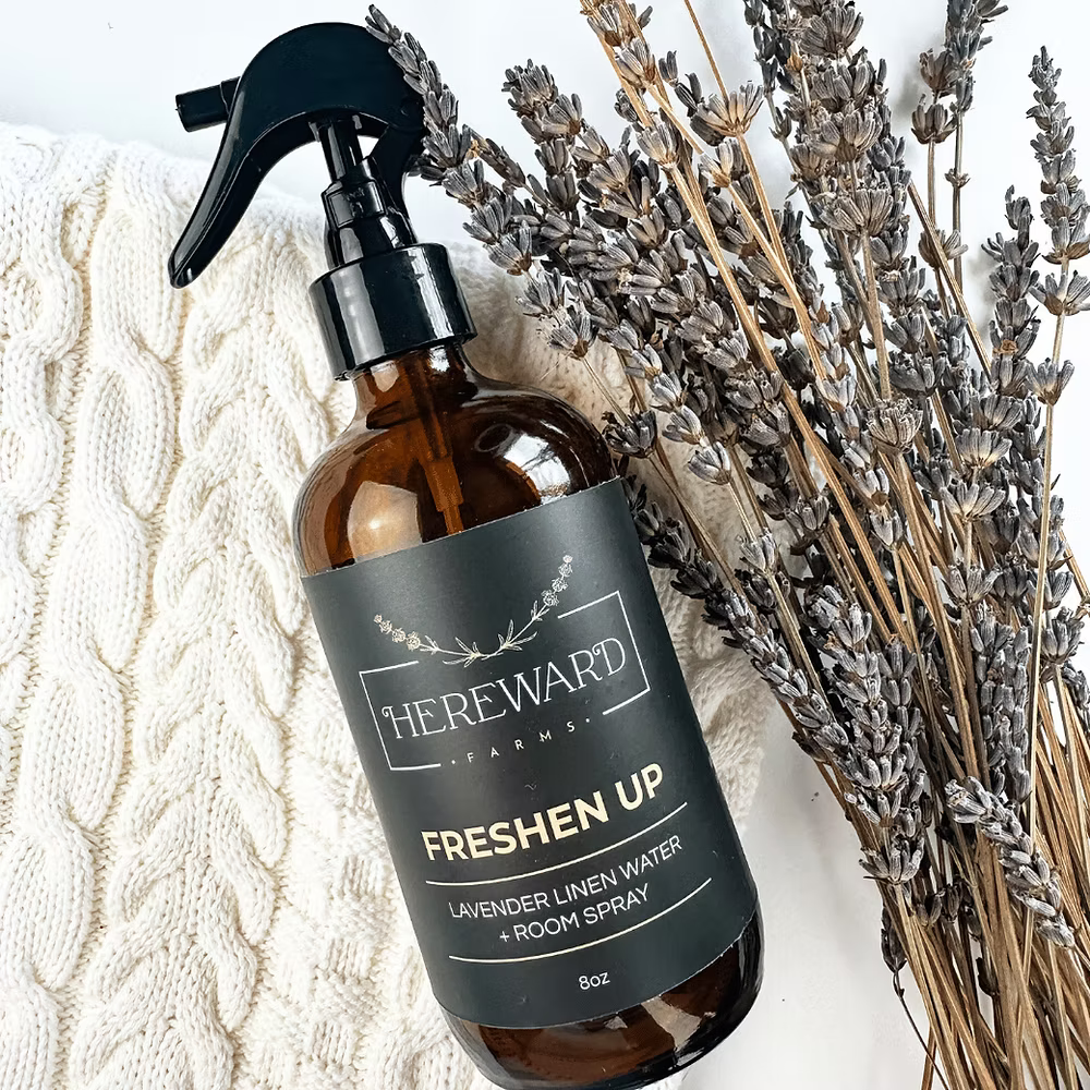 Brown spray bottle labeled 'The Reward' with lavender and a textured white fabric background