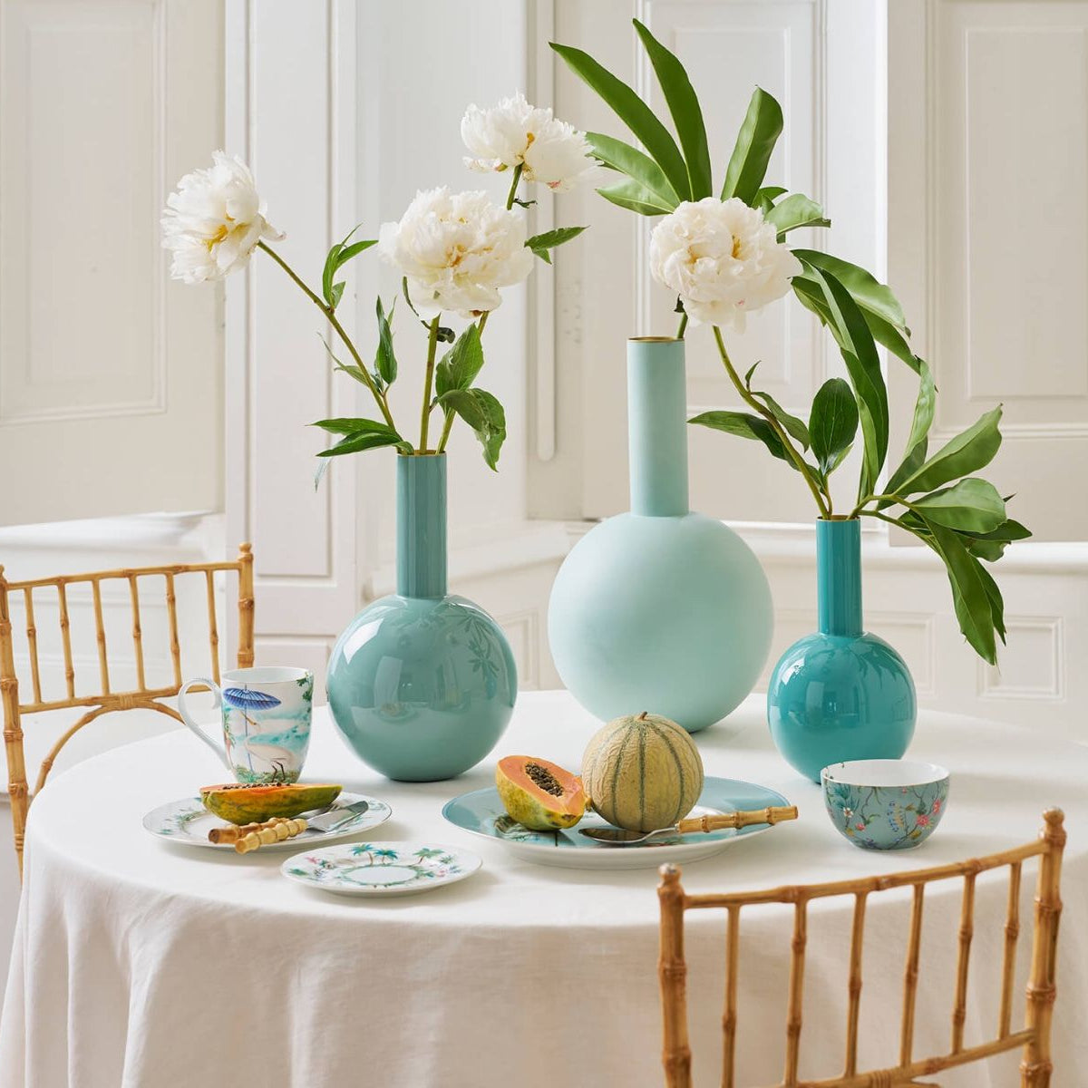 Dining table with decorative vases and flowers in a bright room.