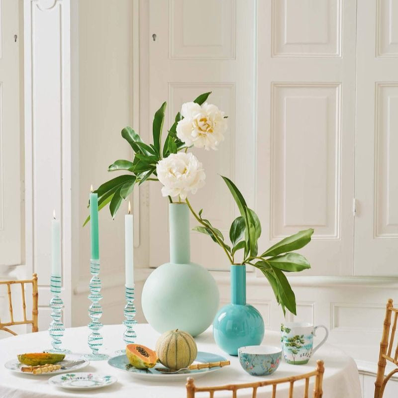 Dining table setting with green and white decor in a bright room.